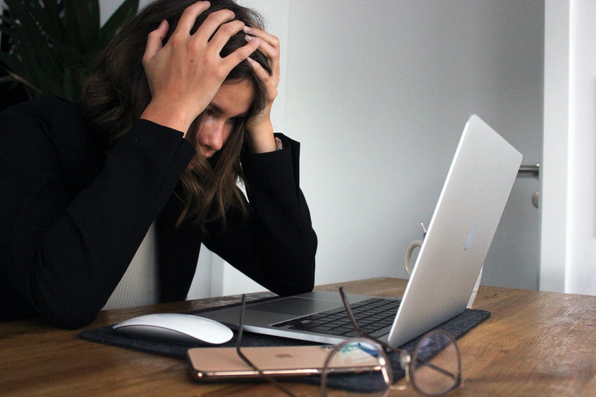 Eine Frau wirkt gestresst vor ihrem Laptop.