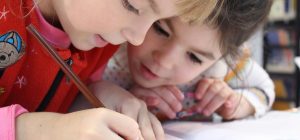 Zwei Kinder lösen gemeinschaftlich Schulaufgaben.