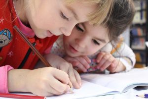 Zwei Kinder lösen gemeinschaftlich Schulaufgaben.
