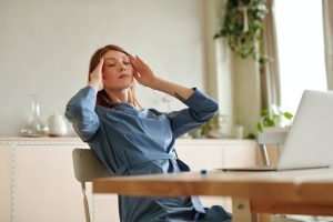 Eine Frau sitzt am Laptop und hält sich den Kopf