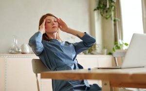 Eine Frau sitzt am Laptop und hält sich den Kopf