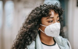 Eine Frau trägt eine Maske. Long Covid Behandlung